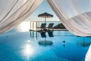 a swimming pool with two chairs and an umbrella at Petani Bay Hotel - Adults Only in Vóvikes