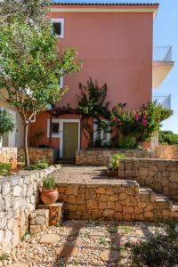 a villa with a stone wall and a house at Petani Bay Hotel - Adults Only in Vóvikes