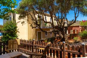 a wooden fence in front of a house with a tree at Petani Bay Hotel - Adults Only in Vóvikes
