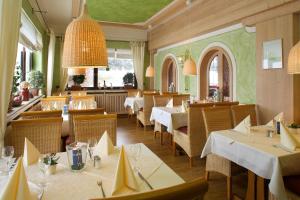 a restaurant with white tables and chairs and windows at Landhotel Seeg in Seeg