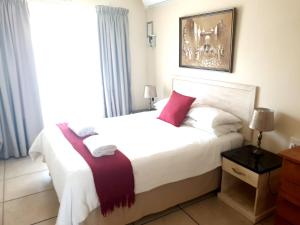 sypialnia z dużym białym łóżkiem z czerwonymi poduszkami w obiekcie St Lucia Palms w mieście St Lucia