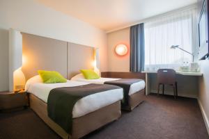 a hotel room with two beds and a desk at Campanile Bydgoszcz in Bydgoszcz