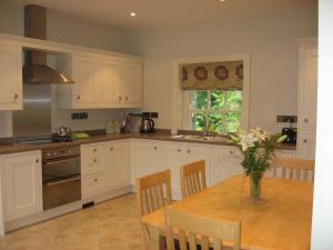 una cocina con armarios blancos y una mesa con un jarrón de flores en Castle View Cottage, en Irvinestown
