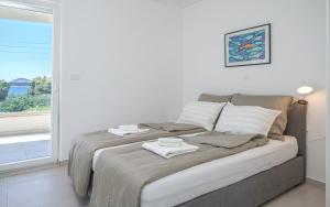 Un dormitorio blanco con una cama con toallas. en Apartment Figtree Vodice, en Vodice