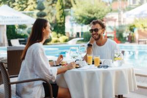a man and woman sitting at a table near a pool at Arcadia Plaza Hotel in Odesa