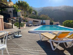 a deck with a swimming pool and chairs and a table at La Casita in El Jaral