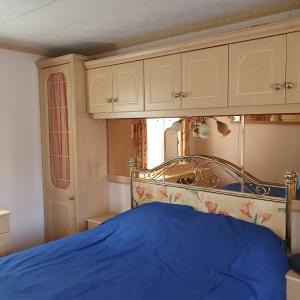 Schlafzimmer mit einem Bett mit blauer Decke in der Unterkunft Saliņmuižas namiņš in Ranka