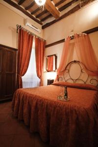 1 dormitorio con 1 cama con manta roja y ventana en Antica Residenza Cicogna, en Siena