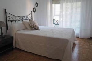 um quarto com uma cama grande com lençóis brancos e uma janela em Apartamento El Parque em Padrón