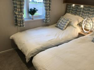 two twin beds in a bedroom with a window at Southview VIP Lodge Skegness Stunning setting and location Outdoor decking area fitted to a 5 star standard in Skegness