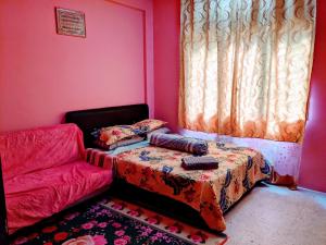 Cette chambre rose comprend un lit et un canapé. dans l'établissement Salam D'Mawar Homestay, à Sungai Coh