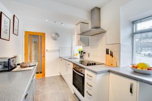 uma cozinha com armários brancos e uma bancada em Greaves Wharf House em Porthmadog