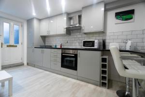Westwood Apartment في ليدز: مطبخ مع دواليب بيضاء وسيارة خضراء على الحائط