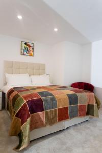 ein Schlafzimmer mit einem Bett mit einer bunten Decke in der Unterkunft Westwood Apartment in Leeds