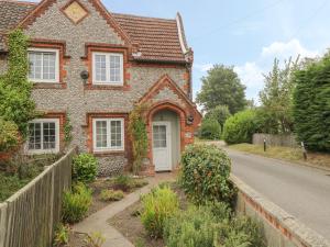 a brick house with a white door on a street at Compass Cottage in Holt