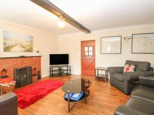a living room with a couch and a fireplace at Compass Cottage in Holt
