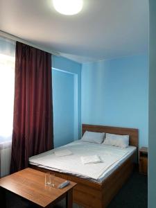 a bed in a blue room with a table at Пана in Almaty