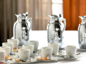 un tavolo con tazze, piattini e lanciatori d'argento di Hotel Begardenhof a Colonia