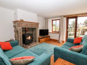 a living room with two blue couches and a fireplace at The Honeypot Cottage in Penzance