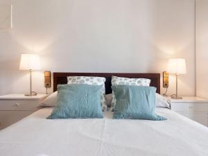 a white bed with two blue pillows and two lamps at Casa de Can Riera con Piscina Comunitaria in Moscari +19 photos