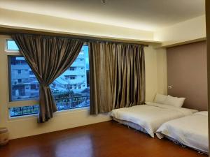 a bedroom with two beds and a large window at Chishang Daoxiang Hotel in Chishang