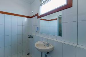a white bathroom with a sink and a mirror at Applewood B&B in Bogor