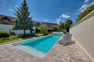 a swimming pool with two chairs next to a house at Logis Maison Gublin - Auberge du Lac in Mesnil-Saint-Père