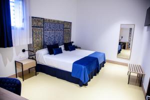 a bedroom with a large bed with blue sheets and a mirror at HOTEL TRIANA MONTALVAN in Seville