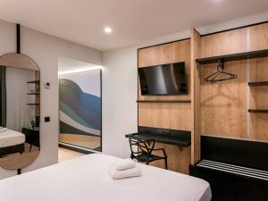 a bedroom with a bed and a tv and a mirror at Ibis Styles Figueres Ronda in Figueres