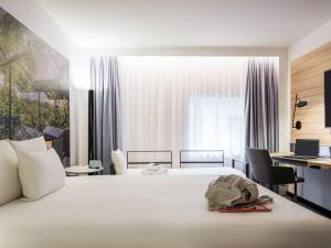 a bed in a bedroom with a white bedspread and pillows at Novotel Den Haag City Centre, fully renovated in The Hague