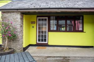 una casa amarilla con puerta y ventana en Yetland Farm Holiday Cottages, en Combe Martin