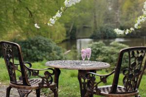 une table avec une vitre assise à côté de deux chaises dans l'établissement Inn On The Lake, à Gravesend