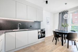 a kitchen with white cabinets and a black table at Old Town Apartments - Św. Barbary street by Renters in Gdańsk