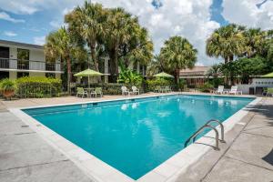 a swimming pool at a resort with chairs and trees at Clarion Inn Conference Center in Gonzales