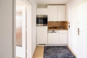eine kleine Küche mit weißen Schränken und einem Waschbecken in der Unterkunft Petras Ammerseeblick in Herrsching am Ammersee