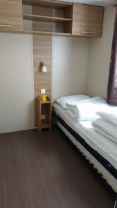 sypialnia z 2 łóżkami i nocną szafką z prześcieradłami w obiekcie Mobil-home Confort camping le bois Masson w mieście Saint-Jean-de-Monts