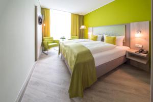 una habitación de hotel con una cama grande y una pared verde en Michels Inselhotel Vier Jahreszeiten en Norderney