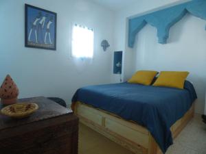 a bedroom with a bed with blue sheets and yellow pillows at Janna d'Ifni in Sidi Ifni