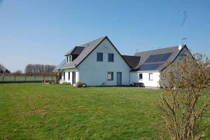 ein großes weißes Haus auf einem Grasfeld in der Unterkunft Blingel, Lovely house with 1st Class Breakfast in Blingel