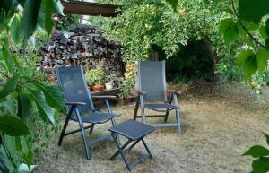 duas cadeiras e uma mesa num jardim em Ferienwohnung Regine Settelmeier em Röttingen