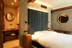 a bedroom with a bed and a sink and mirrors at Nonam Boutique Hotel Gent in Ghent