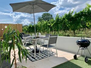 a table and chairs with an umbrella and a grill at Le gîte de Ninon et Léon 2 épis in Eguisheim