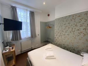 a bedroom with a bed and a tv in it at Swinton Hotel in London