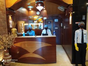 three men standing at a bar in a restaurant at Hotel White House in Kolkata