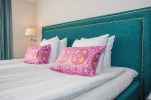 uma cama com almofadas cor-de-rosa e brancas em Mora Hotell & Spa em Mora