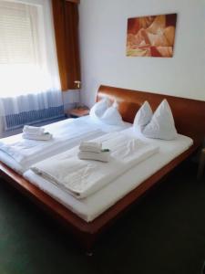 a large bed with white sheets and towels on it at Pension Central in Spittal an der Drau