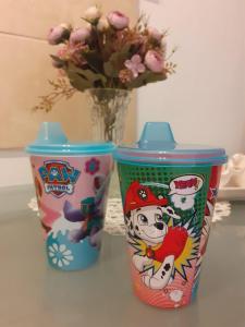 two colorful cups sitting on a table with a vase of flowers at Lavanda in Vukovar