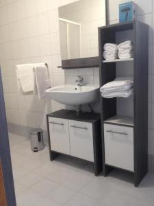 baño con lavabo y estante con toallas en APARTAMENTOS AROMA, en Pag