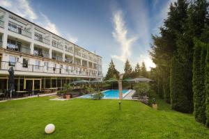 a large building with a pool and lawn chairs at Calimbra Wellness Hotel Superior in Miskolctapolca