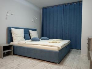 Schlafzimmer mit blauem Bett und blauen Vorhängen in der Unterkunft Квартира в центре на Другетов in Uschhorod